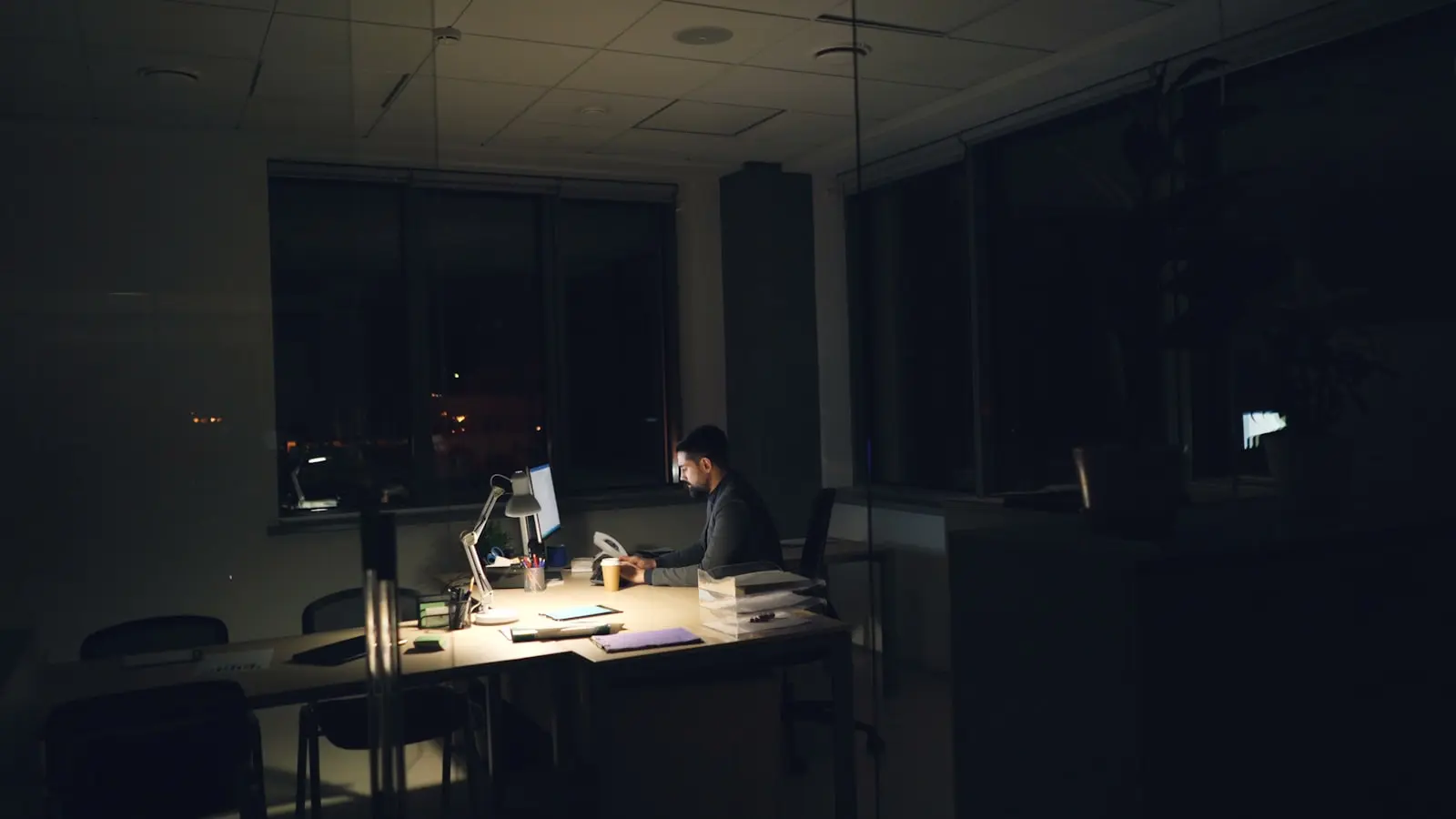 Une personne seule à son bureau tard le soir, dans une flaque de lumière